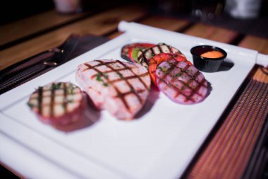 Bir tabak ızgara tavuk göğsü. Izgara patates, domates ve soğan.