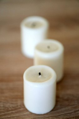 A vertical selective focus shot of a candle on a wooden background
