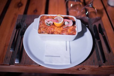 Masadaki parlak tencerede deniz ürünleri lazanyası.