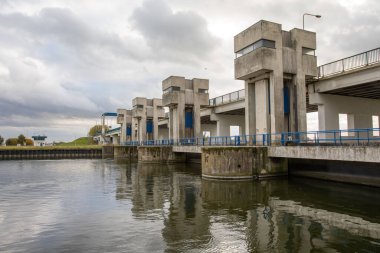 Bulutlu bir gökyüzünün altında nehir üzerinde bir köprü