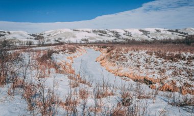 A beautiful shot of a path covered in snow with mountains in the background in a rural area