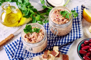 A top view of red beans and herbs in glass jars on the white table
