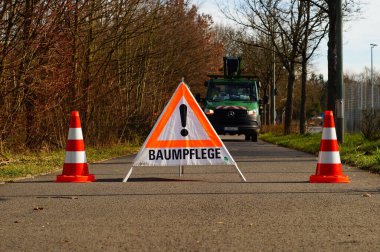 Yol güvenliği için ağaç budamak Frankfurt 'ta bir yolu kapatıyor. Bir işaret ve sütunlar bunu gösteriyor..