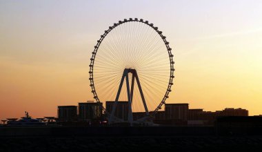 Dubai Dönme Dolabı, gün batımında Dubai 'de. Arka planda binalar var.