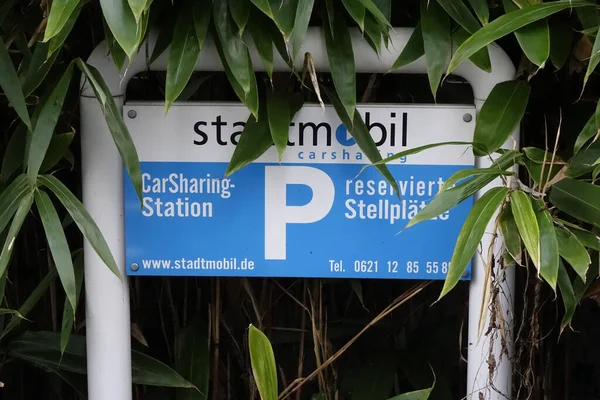 Sign of a parking place exclusively for Stadtmobil carsharing cars, slightly overgrown by green bushes, green mobility