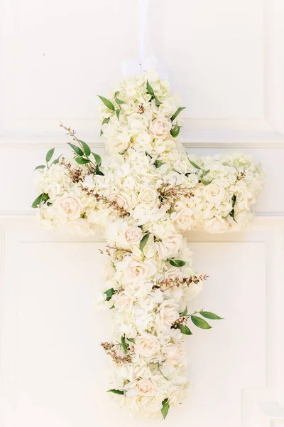 A vertical shot of a floral cross decorated with roses