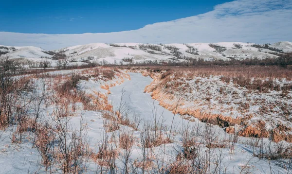 A beautiful shot of a path covered in snow with mountains in the background in a rural area