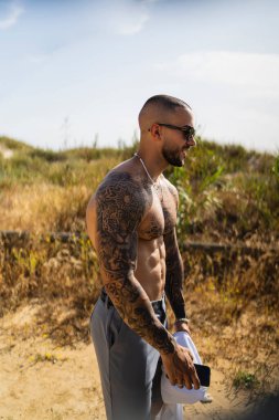 Göğüs ve kollarında dövme olan beyaz bir erkeğin dikey fotoğrafı.