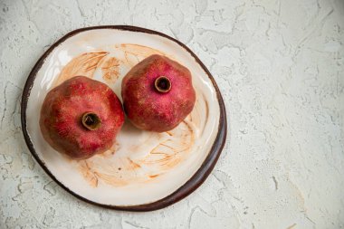A top view of ripe pomegranates on an old plate with leaves design