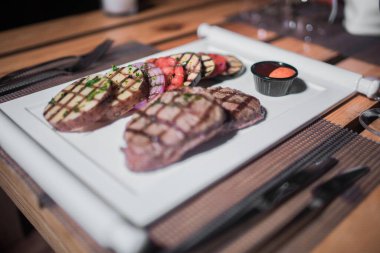 Kızarmış patates, domates ve soğanlı bir tabak et.