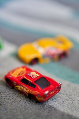 A vertical shallow focus of toy cars on a carpet - Lightning McQueen cartoon characters