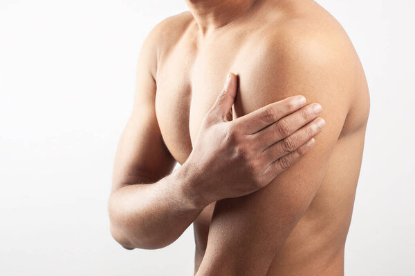 Мужчина без рубашки сжимает мышцы плеча от боли. Изолированный на белом фоне.