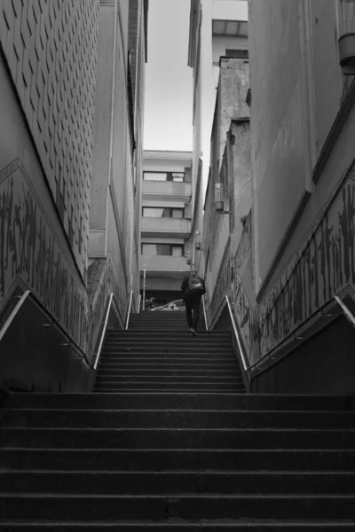 一个男人爬上楼梯间的灰度照片 — 图库照片