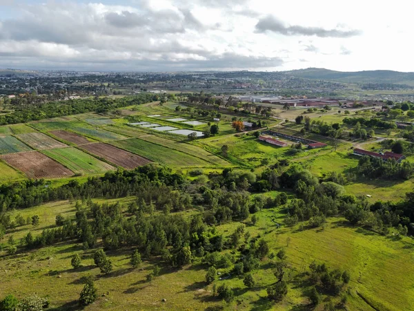 An aerial view of a green landscape with meadows and fields in cloudy sky background