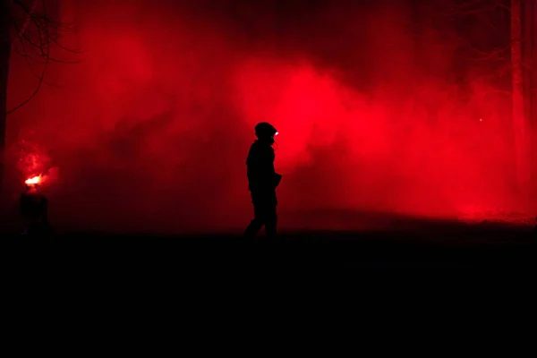 A silhouette of a male fire fighter with burning forest in the background