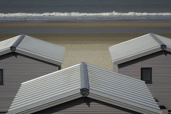 26 March 2022, Zandvoort, North Holland, Netherlands, Beach huts at North Sea beach with rolling waves in the background (horizontal)