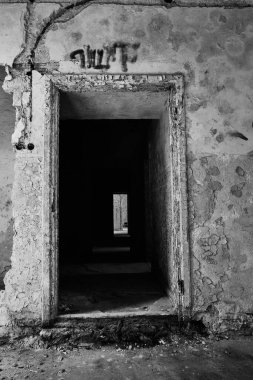 Terk edilmiş psikiyatri bölümü binasının iç kısmının dikey gri tonlu görüntüsü.