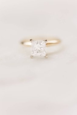 Beyaz arkaplandaki elmas nişan yüzüğünün dikey yakın çekimi.