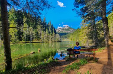 A beautiful view of a woman sitting on a bench and looking at the mountains