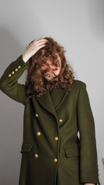 Gri bir arka planda poz veren kıvırcık saçlı bir kızın yavaş çekim hızı.