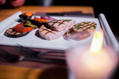 Bir tabak ızgara tavuk göğsü. Izgara patates, domates ve soğan.