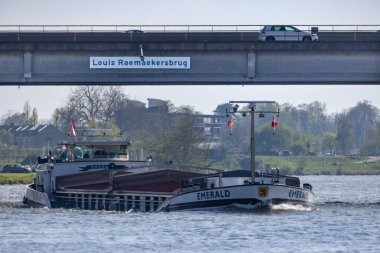 A cargo boat on the river Maas in Roermond going under the Louis the Raemaekers bridge