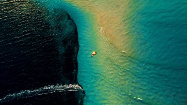 A mesmerizing aerial drone shot of the ocean water and a kitesurfer surfing alone at sunset