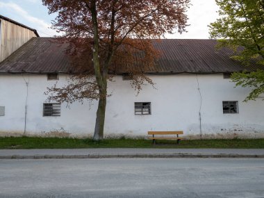 A closeup shot of a red roofed building in a village behind the tree