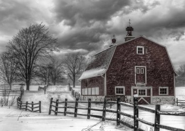 A grayscale shot of a barn in the snowy countryside under a gloomy sky clipart