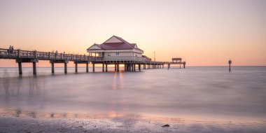 Manzaralı gün batımında deniz kenarında bir evin olduğu büyüleyici bir deniz manzarası.
