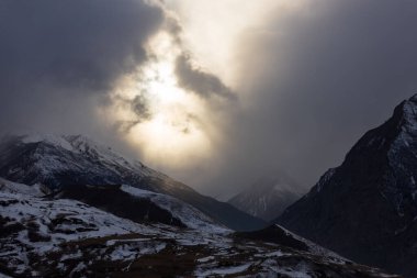 A breathtaking shot of high mountains covered with snow in very cloudy cold weather