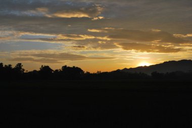 A scenic sunset with mountain silhouette against a golden sky