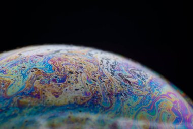 Sabun köpüğünün yarısı. Yakın plan. Siyah arka plan. Parlak renkler. Yan görüş. Bilinmeyen bir gezegenin taklidi. Bilim kurgu