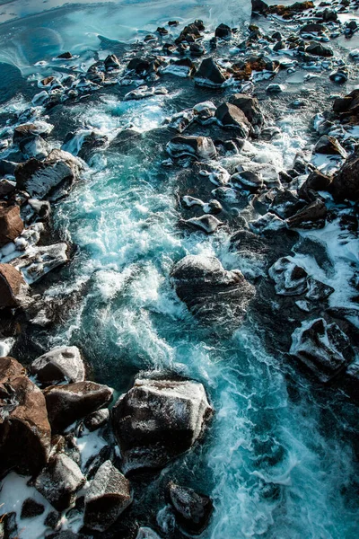 Reykjavik, İzlanda 'da kışın karla kaplı kayalara su sıçrayan dikey bir çekim