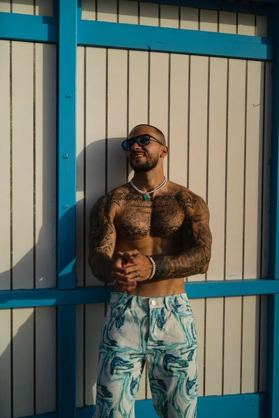 Mavi-beyaz kravat desenli kotlu, üstsüz, genç bir dövmenin dikey görüntüsü.