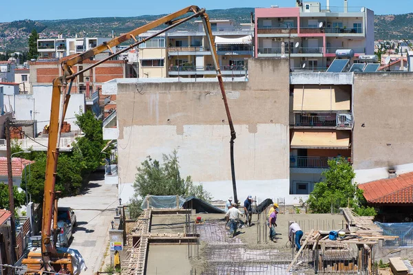 İnşaat işçileri, şehir merkezinde ev inşaatı. Beton ve beton döken özel bir tekerlek makinesinin yardımıyla. Volos Şehri, Yunanistan