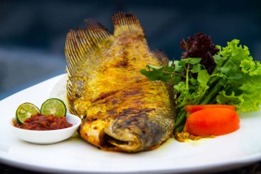 Beyaz bir tabakta yanında marul olan ızgara bir balığın güzel bir resmi.