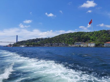 Travel by ferry in front of the bridge on the Bosphorus.Beautiful buildings and mansions on the coast, on a hillside with a green forest