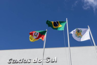 Brezilya, Rio Grande do Sul Eyaleti ve Caxias do Sul şehir bayrakları güneşli bir günde rüzgarda dalgalanıyor