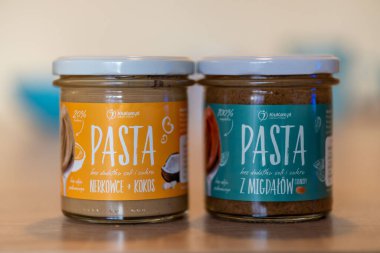 Two Krukam brand almonds and coconut with cashew paste in a glass jar on a table.