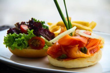 Güzel bir porsiyon somon burger, marul, domates burger ve patates kızartması.