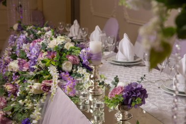 Açık mor renkli çiçeklerle süslenmiş bir düğün masası.