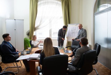 Modern ofisteki iş arkadaşlarıyla birlikte çalışırken yeni proje sunan başarılı iş adamları