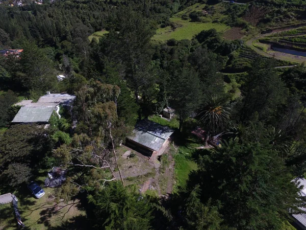 Güneşli bir günde yeşil ormanlarla kaplı tepelerin ve kırsal alandaki evlerin kuş bakışı görüntüsü