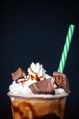 A frappe coffee with chocolate pieces and a straw isolated on black background