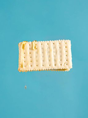 Mavi arka planda izole edilmiş kraker kurabiyesinin dikey görüntüsü.