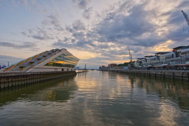A beautiful view of Hamburg harbor building under cloudy sky with reflection in the river