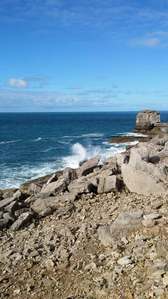 Вертикальный Снимок Береговой Линии Камнями Камнями Голубым Небом — стоковое фото