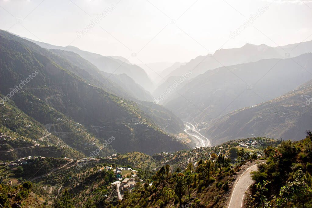 A misty Himalayan mountain range valley with winding road