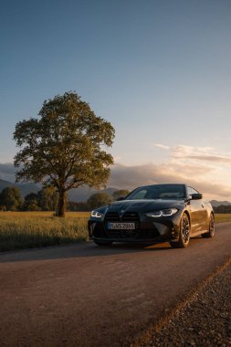 Günbatımında modern bir BMW M4 'ün, Dağ v. lüks spor arabalı görüntüsü birçok sürücünün hayalindeki arabadır.
